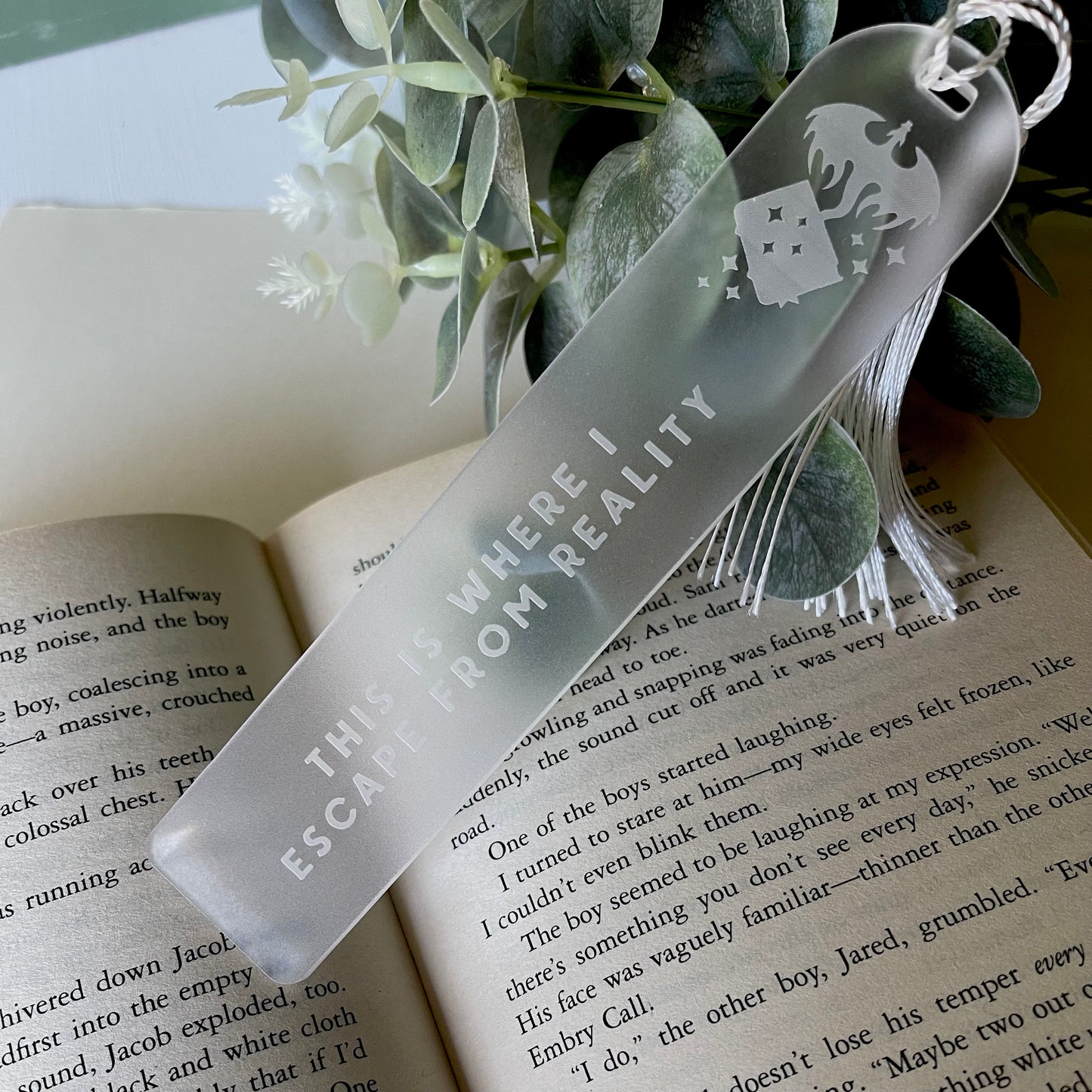 Clear bookmark with text on an open book with greenery in the background